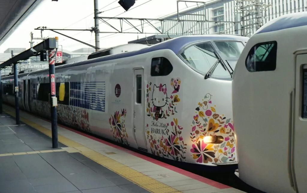 Colorful Hello Kitty themed train at a railway station in Kyoto, Japan.