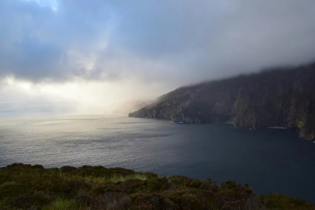 Dramatic cloudy view of Slieve League cliffs and ocean at twilight.
