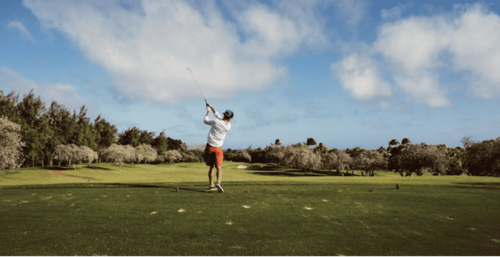 A man swinging a golf stick on a golf course