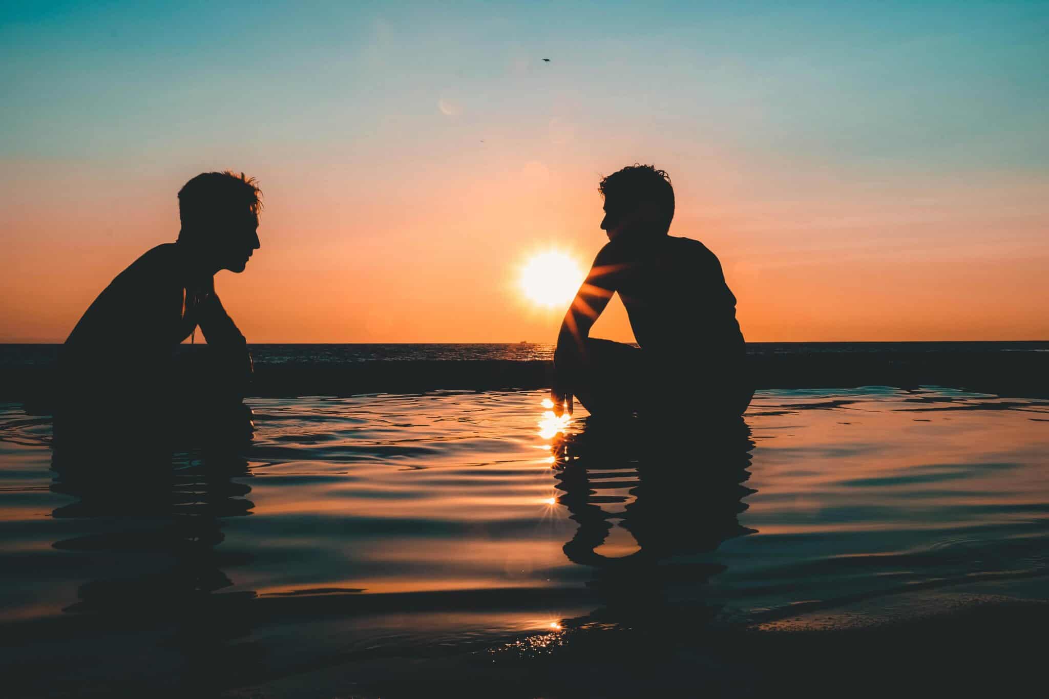 Two people silhouetted against a vibrant sunset at Laguna Beach, creating a peaceful and tranquil scene.