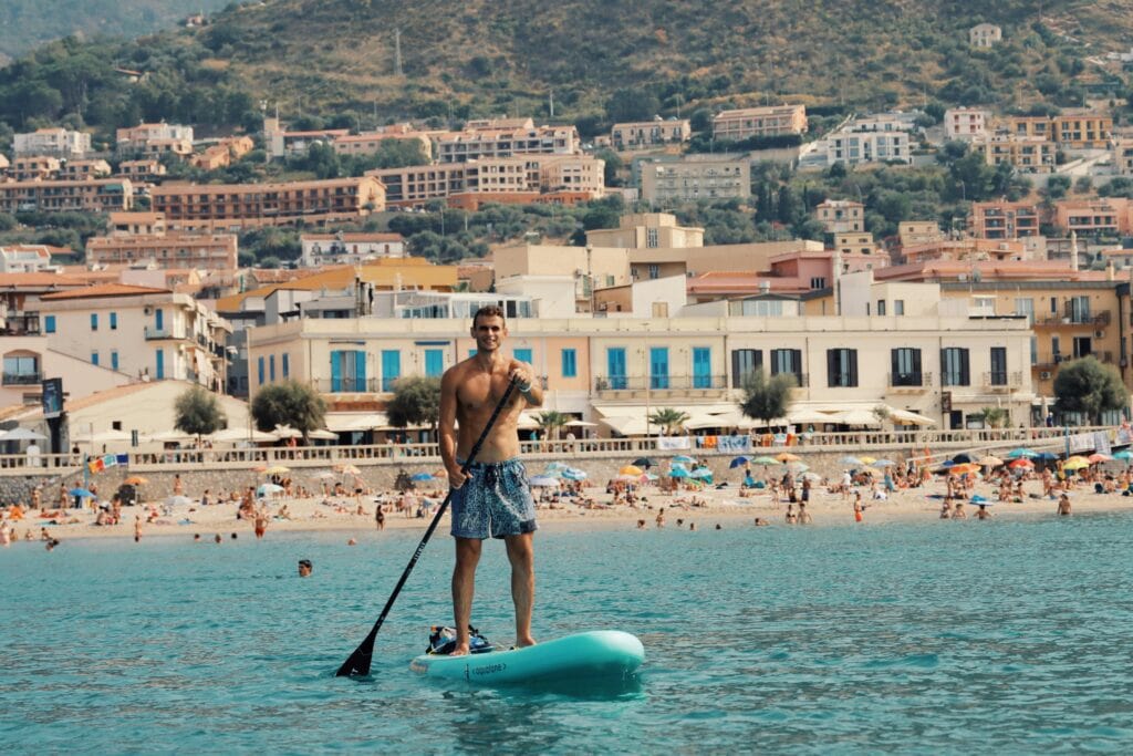 Enjoy a summer paddleboarding adventure in Cefalù, Sicily against a charming coastal backdrop.
