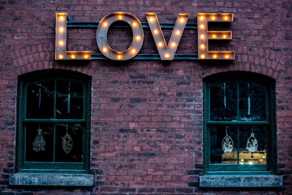 Illuminated love sign on a historic brick building in Toronto's Distillery District.
