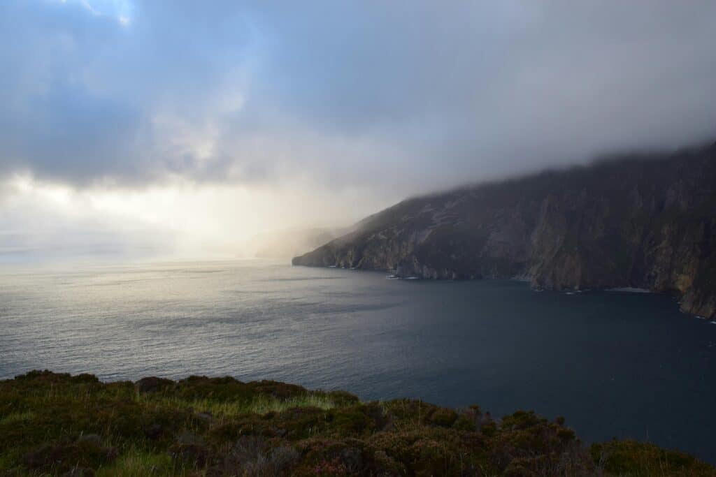 Dramatic cloudy view of Slieve League cliffs and ocean at twilight.