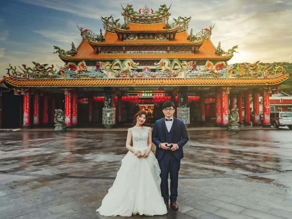 A couple poses for a wedding photo in front of the elaborate Dongxing Temple in Taiwan.