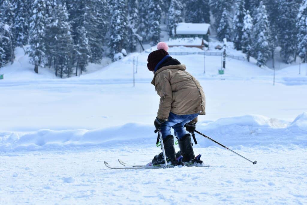 A child in a brown jacket skiing in a snowy landscape, capturing the essence of winter sports fun.