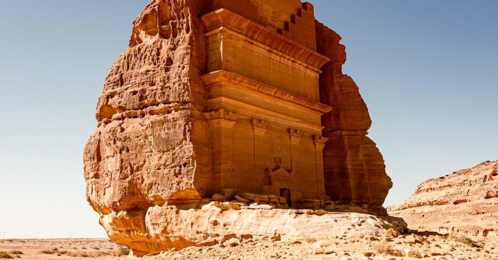 Sunlit rock-cut tomb in AlUla's desert landscape, Saudi Arabia.