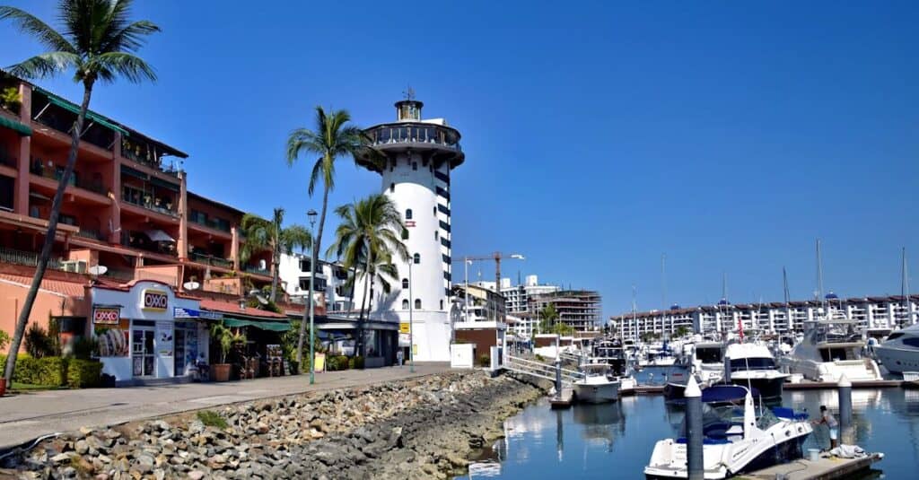 Scenic view of Marina Vallarta lighthouse and waterfront boats under a clear blue sky.