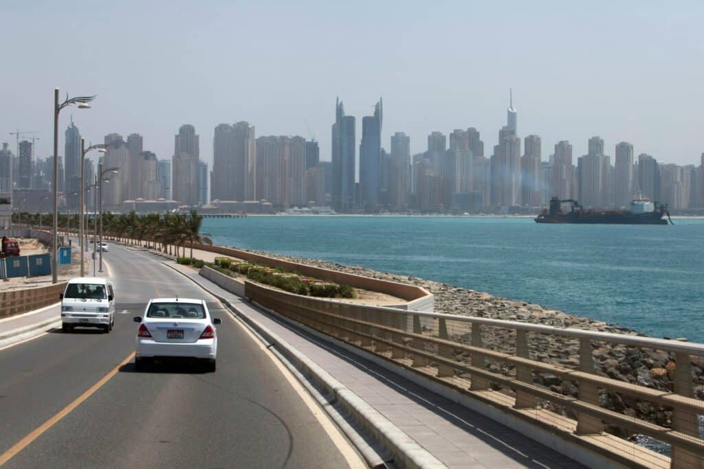 Scenic Dubai skyline with modern skyscrapers and waterfront road under clear sky.