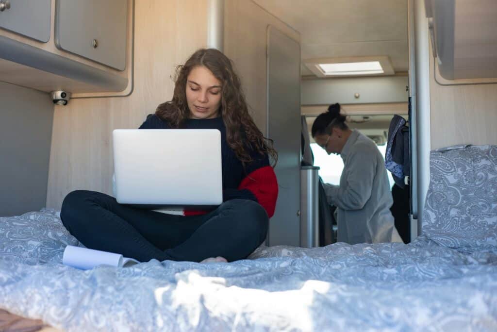 Young woman focused on using a laptop inside a camper van, enjoying a mobile lifestyle.