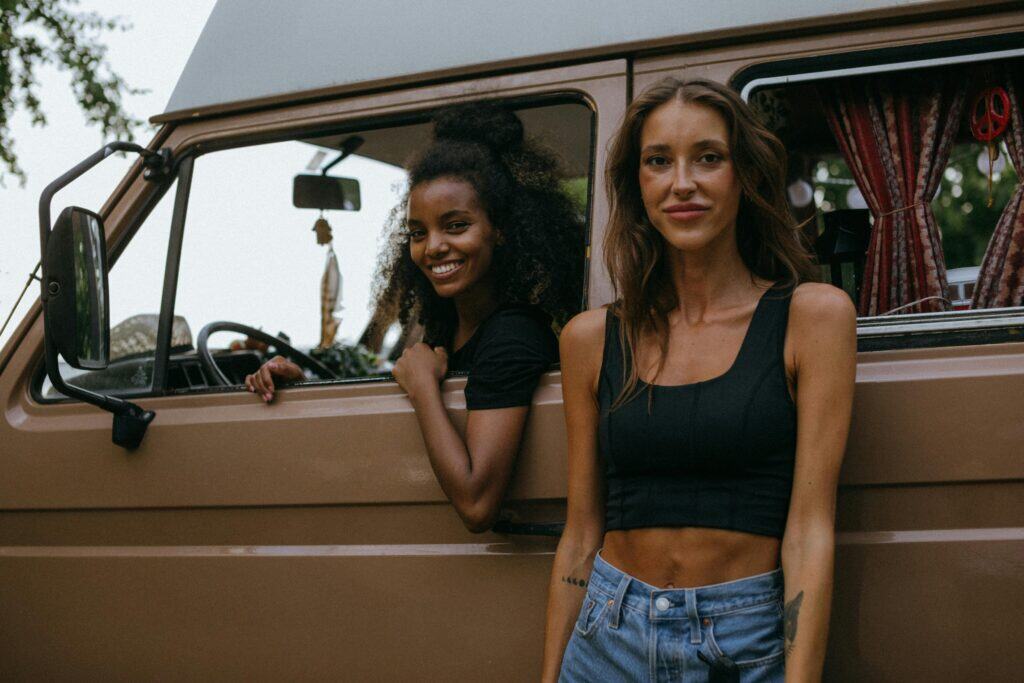 Smiling friends enjoying a summer road trip in a classic van. Outdoor adventure awaits.