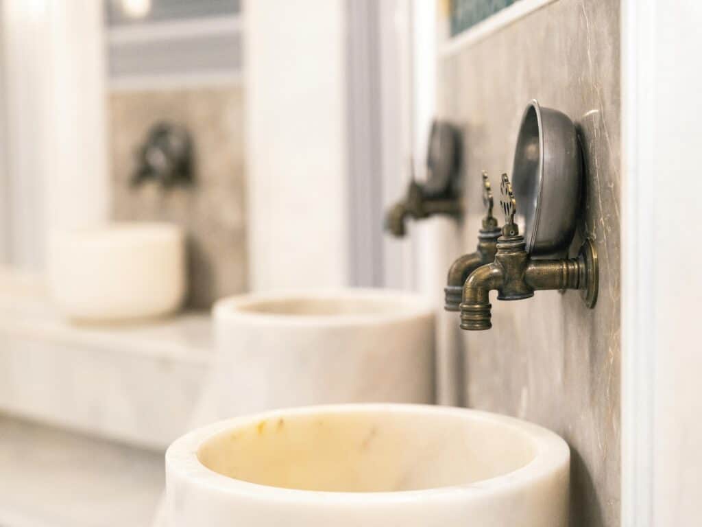 Close-up of vintage Turkish bath faucets with marble basins, showcasing traditional design.