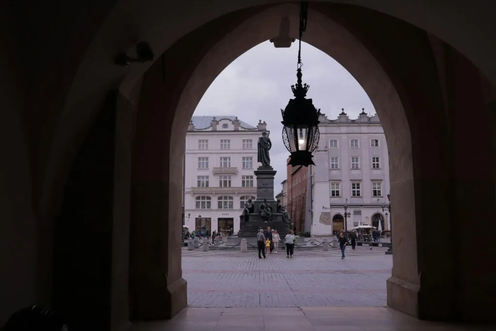 View of the Adam Mickiewicz Monument in Krakow's historic Old Town, showcasing the city's architectural charm.