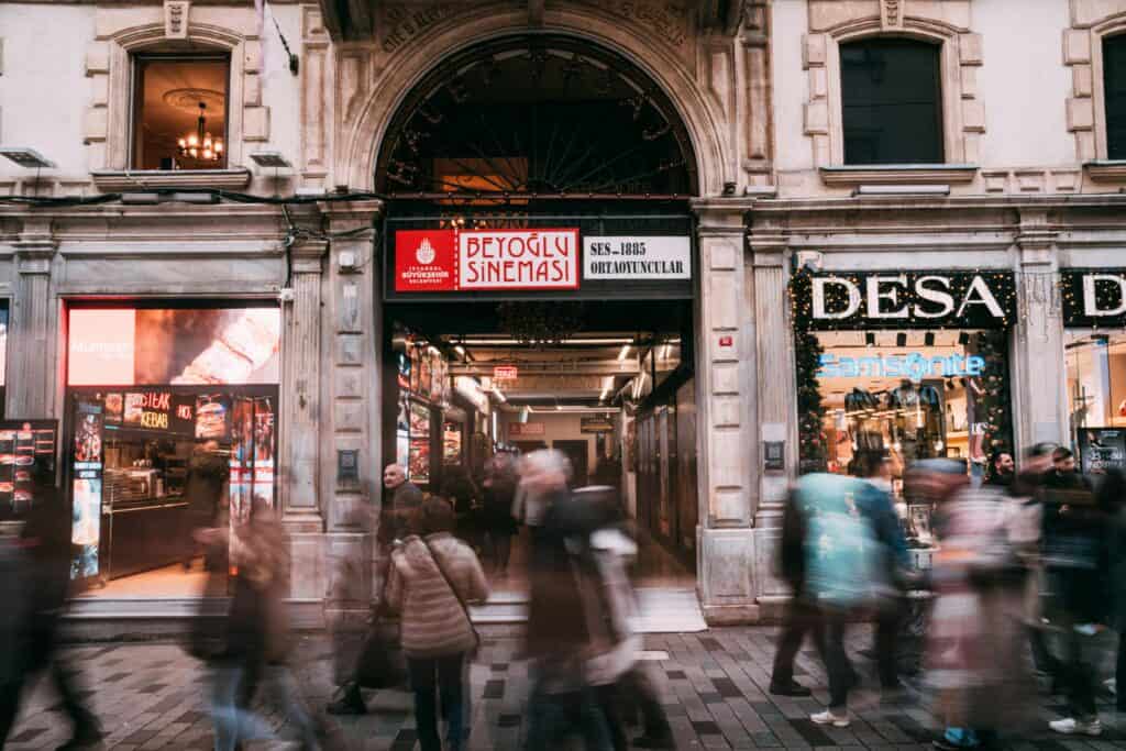 Blurred pedestrians at Beyoğlu Sineması in Istanbul, capturing vibrant urban life and historical architecture.