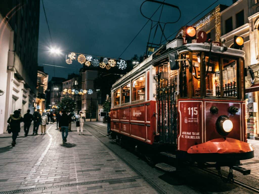 A vibrant night scene in Istanbul featuring a historic tram and festive holiday decorations on a bustling street.