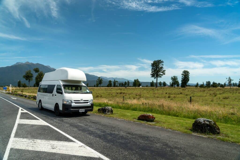 Campervan parked on a picturesque rural road under a clear blue sky.