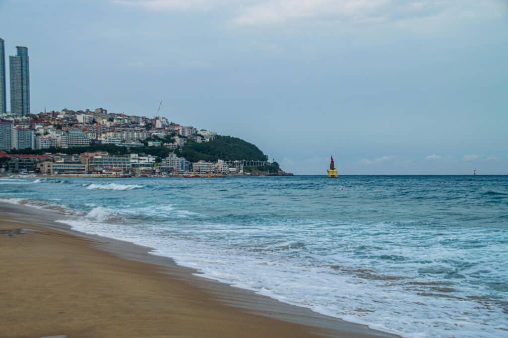 Tranquil scene of Haeundae Beach with city skyline and ocean in Busan, South Korea.