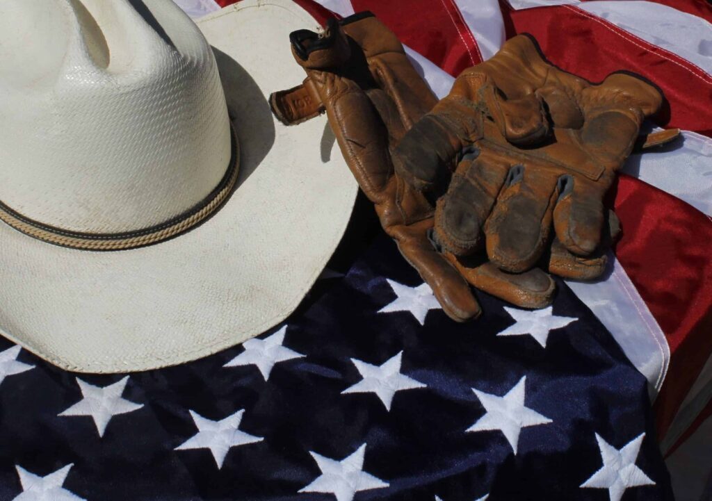 A cowboy hat and gloves resting on an American flag, symbolizing patriotism.
