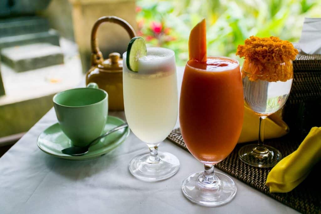 A vibrant assortment of drinks on a tropical Bali table setting, featuring fresh juice and floral decor.