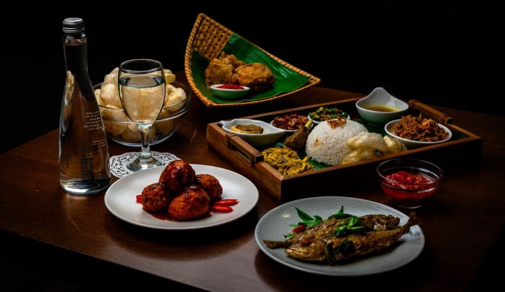 A vibrant and traditional Indonesian meal with various dishes served indoors on a wooden table.
