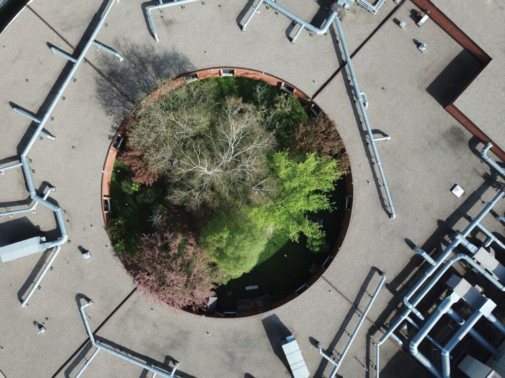 Drone shot of an architectural courtyard highlighting lush greenery surrounded by rooftop structures.