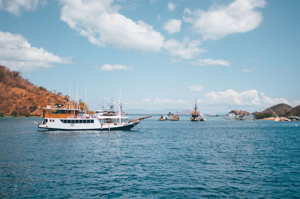 Traditional ships sailing in the clear waters of Komodo, Indonesia under a sunny sky.