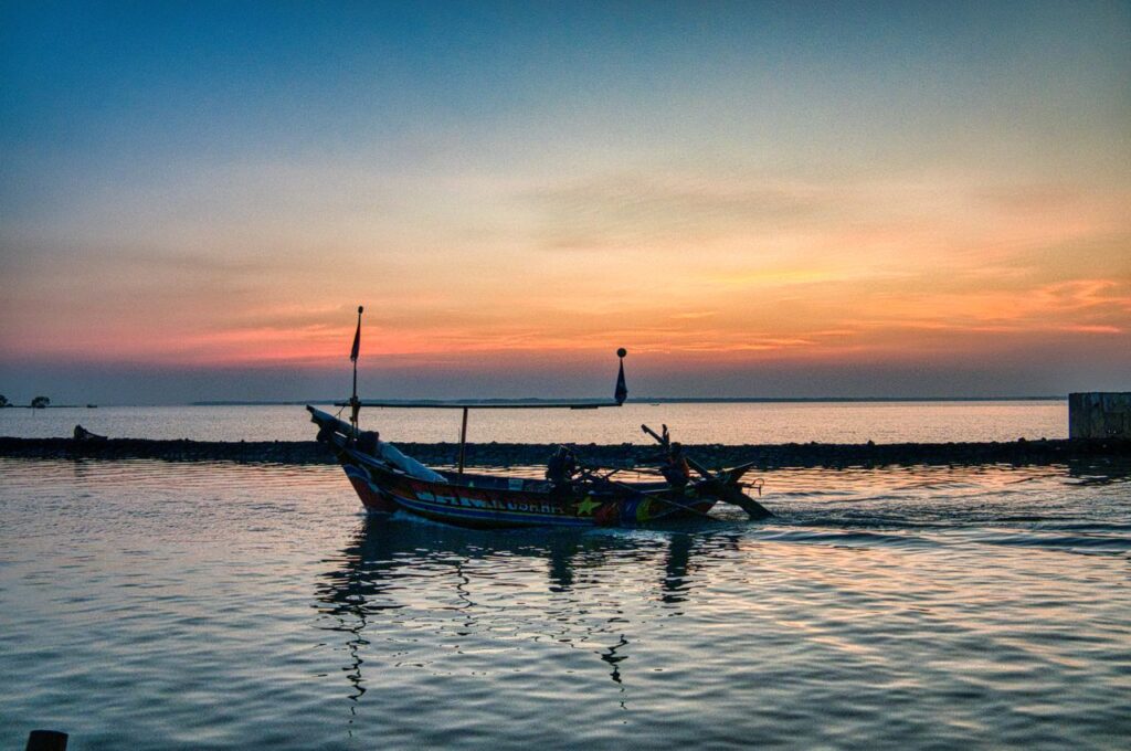 Scenery view of boat moored on rippled sea near pier under cloudy sky in harbor at dusk