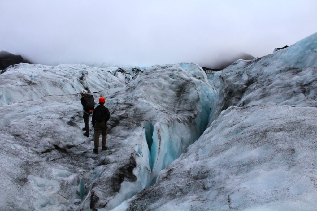 Two adventurers explore a glacial landscape in Iceland, experiencing the raw beauty of nature.