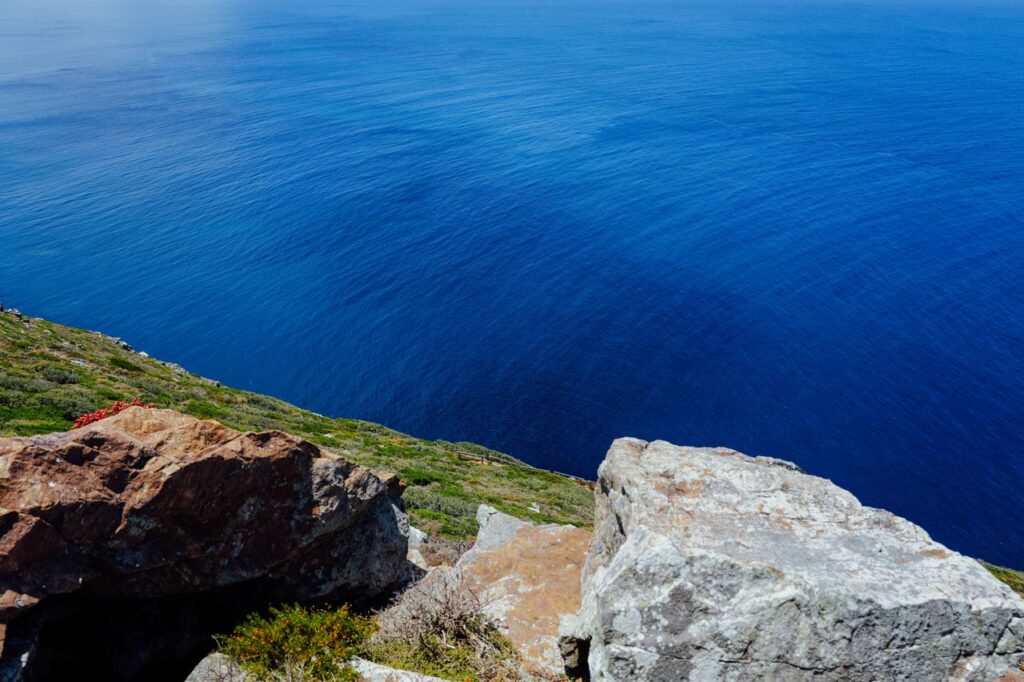 Vibrant coastal cliff scene overlooking an expansive deep blue ocean with natural rock formations.