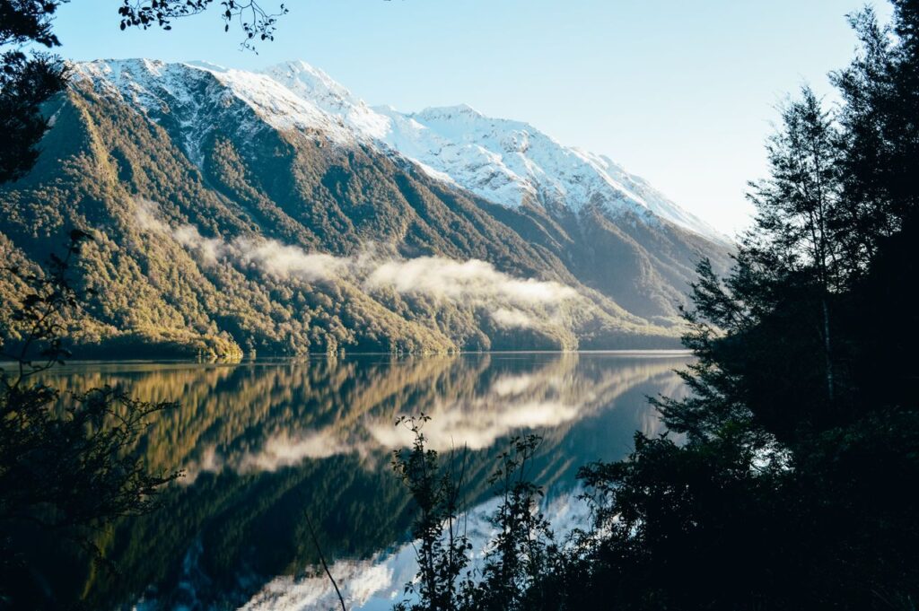 Breathtaking view of snow-capped mountains reflecting in a serene lake in Southland, New Zealand.
